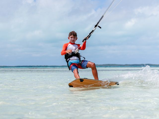 Menino velejando de kitesurf em água rasa e cristalina